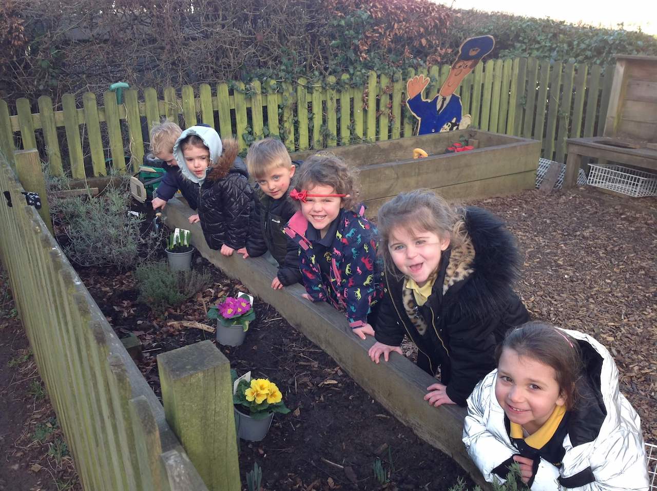 Six happy children potting plants in the Pre-school garden.