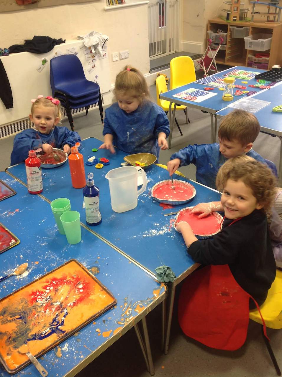 Four happy children, busy painting at a table